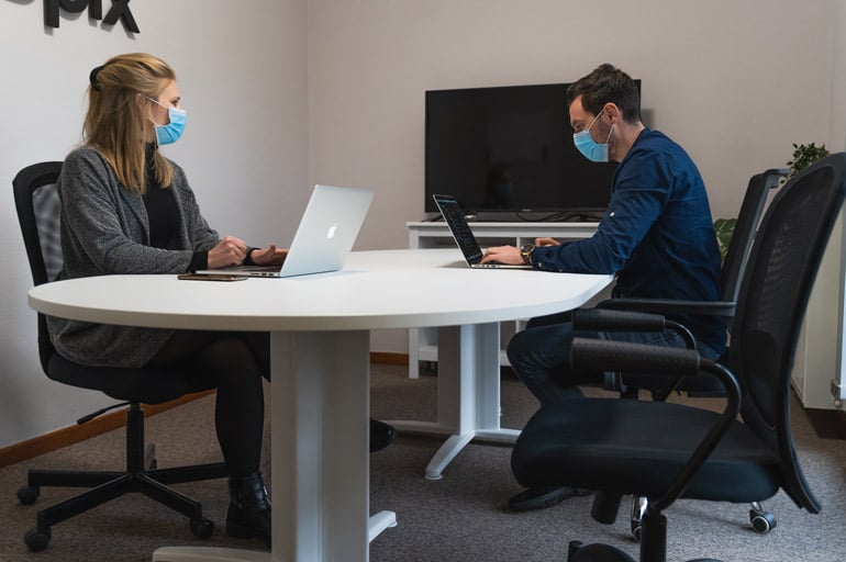 coworkers-sitting-office-room-wearing-masks